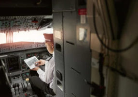 Airline Pilot on Tablet Device in Cockpit