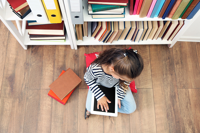 child using ipad in library in secret, managing student device usage in schools